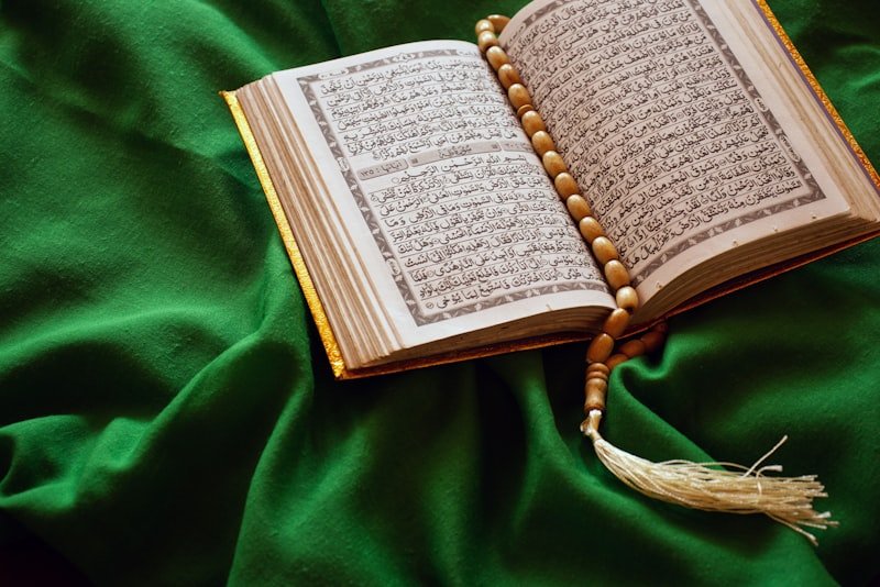 An open Qur'an with prayer beads on green velvet